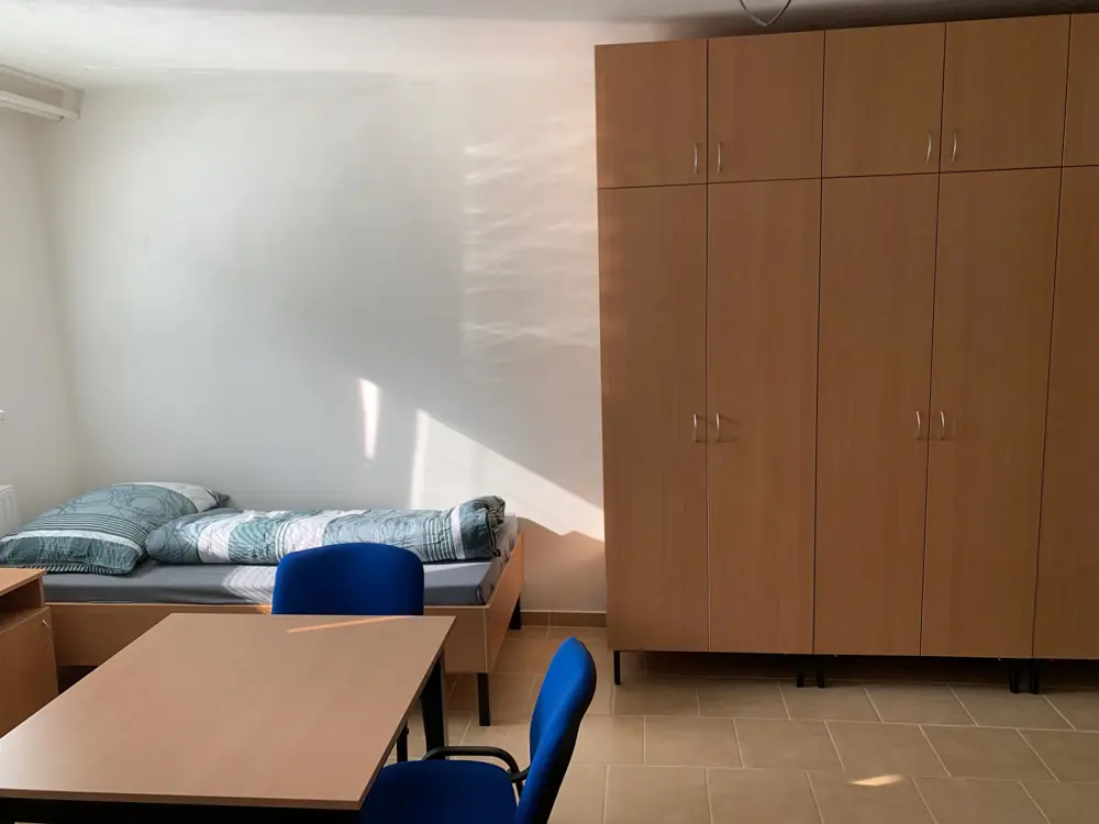 Кімната з ліжком, столом і великою шафою в житлі у Вратімові